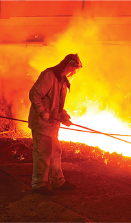 Worker handling molten metal in furnace